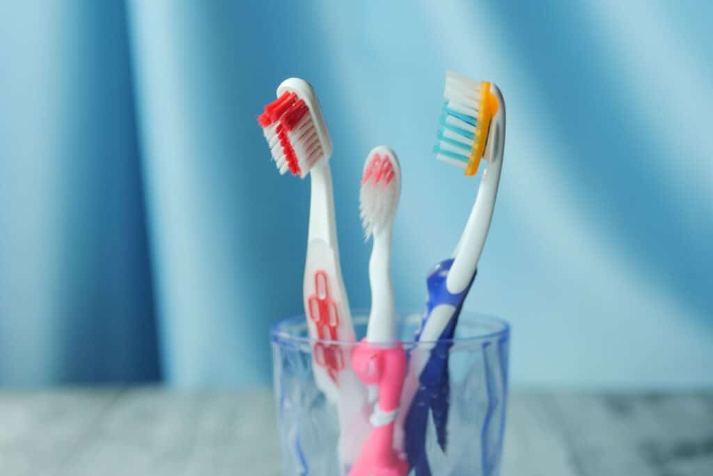 Drei Zahnbürsten in einem Glas im Badezimmer
